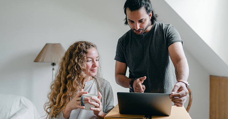 Woman and man looking at laptop on top of cardboard box.