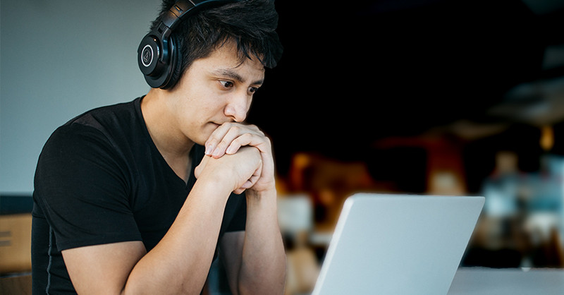 Young man looking at laptop with headphones